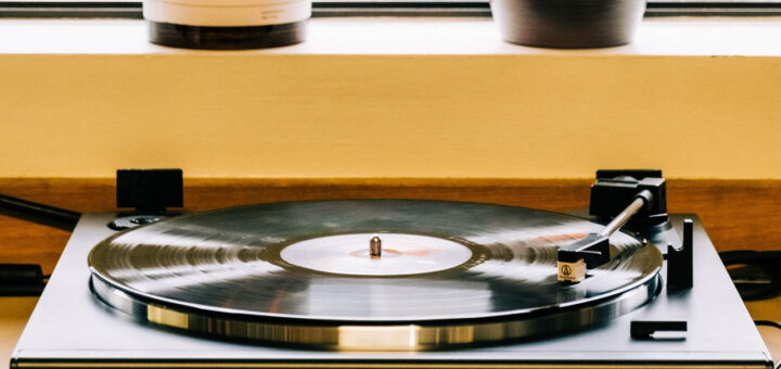 Turntable with vinyl record in front of window with candle and plant.